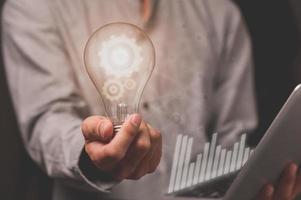 A business man's hand holds a light bulb with a gear icon photo