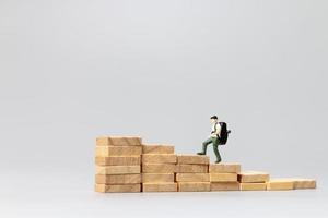 Miniature people, traveler standing on wooden blocks on a gray background. Travel and adventure concept photo