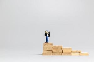 Miniature people, traveler standing on wooden blocks on a gray background. Travel and adventure concept photo