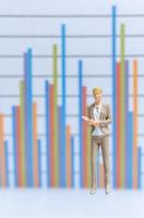 Miniature businesswoman standing on business graph background, business growth concept photo