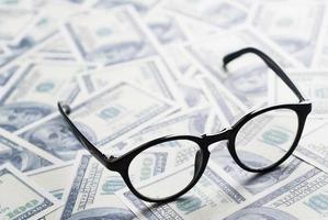 One hundred dollar banknotes background with eyeglasses. photo