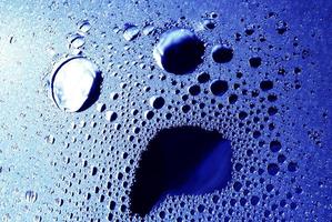 Water surface with a face-like shape. Abstract bubbles background in blue monochrome. photo