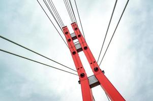 Bottom view of a red bridge tower with steel wires photo