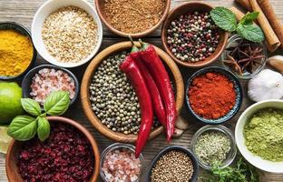 A selection of various colorful spices on a wooden table in bowls and spoons photo