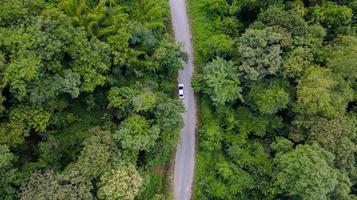 Aerial top view car driving through the forest on country road, view from drone photo