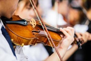 Cerrar las manos del jugador de violín, estudiante violinista tocando el violín en concierto de orquesta foto