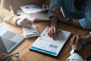 Young accountant marketing team consulting and using a calculator to analyze sales growth in the global workplace market. Accounting concept photo