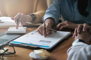 Young accountant marketing team consulting and using a calculator to analyze sales growth in the global workplace market. Accounting concept photo