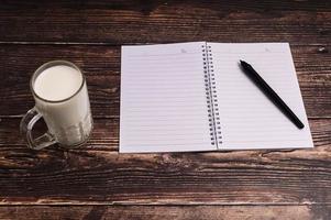 Notebook and a glass of milk on the desk photo