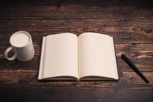 Notebook and a glass of milk on the desk photo