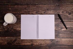 cuaderno y un vaso de leche en el escritorio. foto