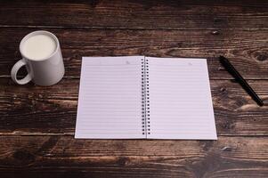 Notebook and a glass of milk on the desk photo