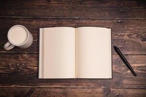 An open notebook and a cup of coffee on a wooden table photo