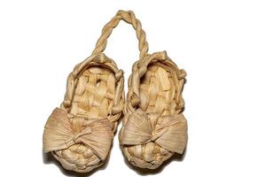 Two wicker bast shoes tied together on a white background photo