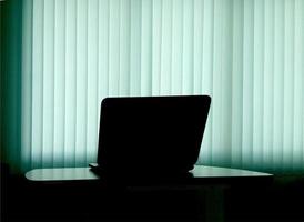 Silhouetted notebook on table with blind light curtain photo