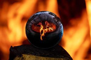 Fogata en una chimenea envolvente de piedra reflejada en una bola de cristal foto