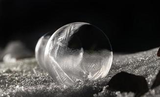 Detail shot of a frozen soap bubble on snow-covered ground at night