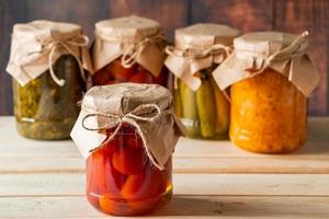 Jars of fermented vegetables on wooden background photo