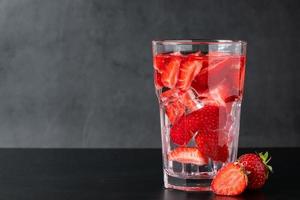Bebida de hielo con fresas sobre fondo negro foto