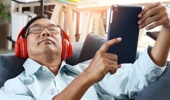 Elderly Asian man sitting at home on a holiday listening to music happily photo