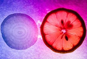 Captura macro de rodajas finas de cebolla y limón, con iluminación de colores y retroiluminación foto