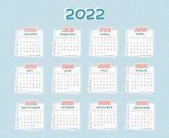 Horizontal Calendar for 2022 from January to December. Every month is on squared paper with dots, piece of newspaper is at the bottom, pink scotch, color patterned adhesive tape is on the top vector