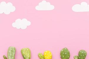 pequeños cactus con nubes de papel sobre fondo rosa foto