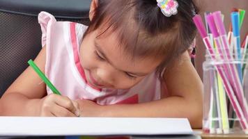 Cerca de niña sentada en un escritorio para colorear video