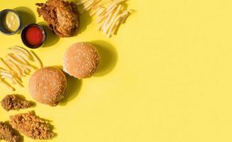 Top view fried chicken burgers and fries with copy space on yellow background photo
