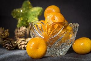 jarrón de cristal con una mandarina sobre fondo gris. foto