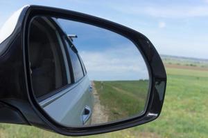 Car mirror on a background of green fields. photo