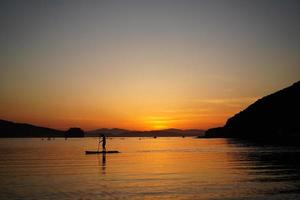 Beautiful sunset with silhouettes of people on SUP-surfer.