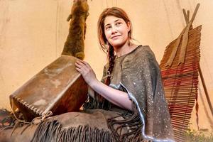 Young Lakota girl sits in a tipi and makes a rawhide box photo