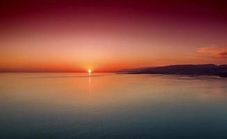 puesta de sol sobre un mar en calma desde la altura del vuelo de las aves foto