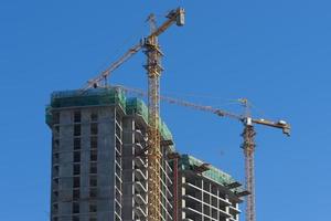 house under construction and cranes against the blue sky. photo