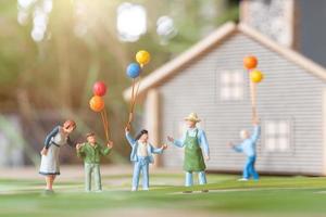 gente en miniatura, familia feliz jugando en el césped del patio trasero. concepto de vida en casa foto