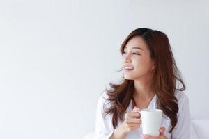 Retrato de joven mujer asiática sosteniendo una taza de café sobre un fondo blanco.