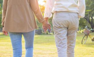 Elderly couple hold hands and happily strolling in the park on holiday photo