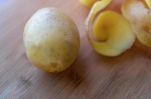 patatas crudas con cáscara sobre una tabla para cortar foto