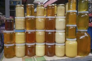 honey of different color in banks on a counter for sale. photo