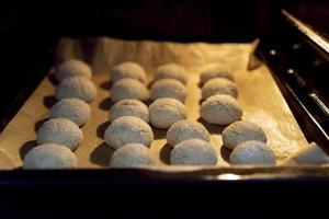 Oven with cookies on a baking sheet on parchment. photo