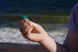 Child's hand with sea glass on the sea background. photo