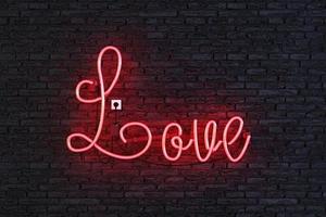 Red neon lamp with the word LOVE on dark brick wall photo