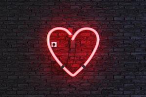 símbolo del corazón en la lámpara de neón roja con pared de ladrillo oscuro foto