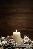White candle lit with pine cone ornaments photo