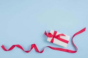 Red ribbon near gift box on blue background