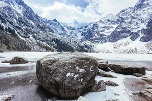 rocas cerca de un lago con montañas en invierno