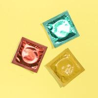 Top view colourful condoms on yellow background photo