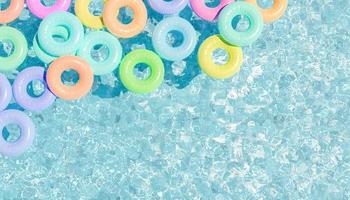 Top view of swimming pool with lots of pastel colored floats, 3d render photo