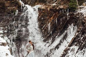 novios en la cascada de la montaña foto